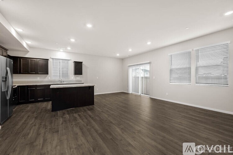 A spacious kitchen with dark wood flooring and white walls.