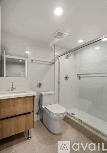 A bathroom with a toilet, sink, and glass shower stall.