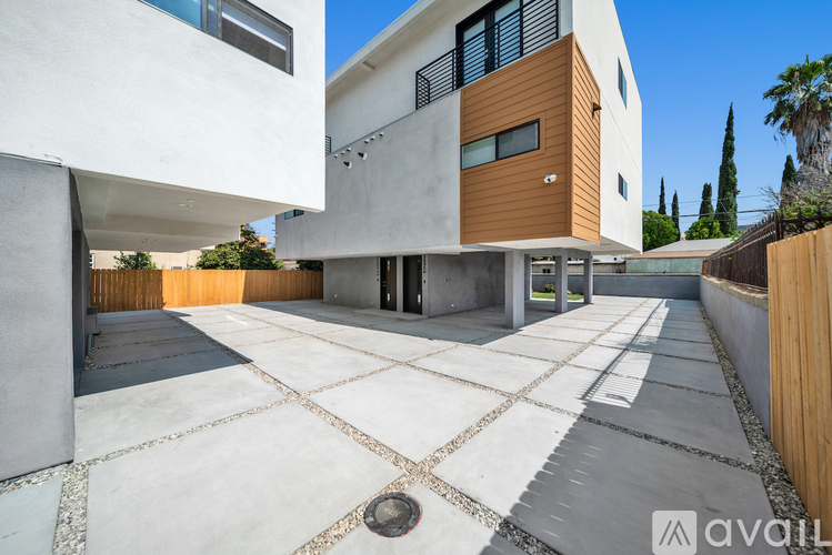 A modern house with a white and brown exterior and a tiled driveway.