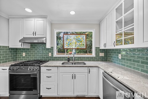 A kitchen with white cabinets and a green backsplash.