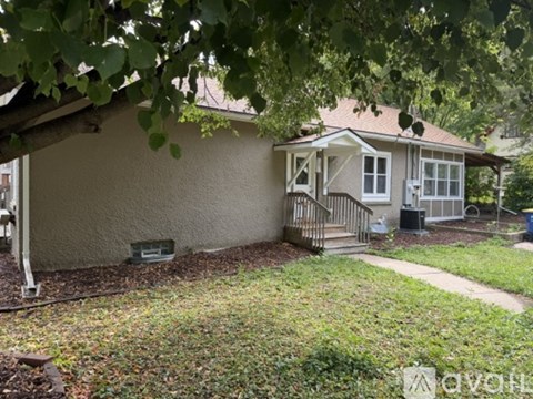 A house with a front porch and a tree branch hanging over it.