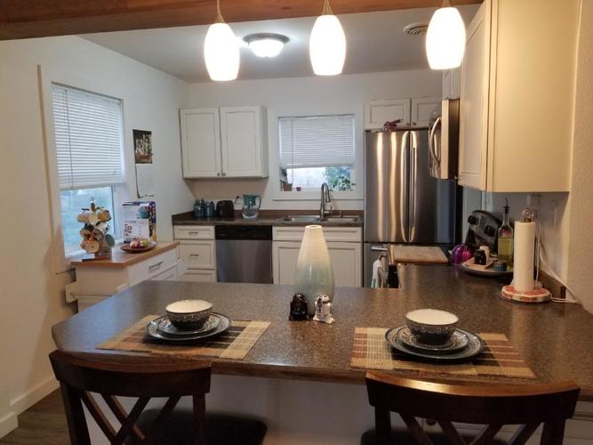 A kitchen with a table set for two with a view of the refrigerator and sink.