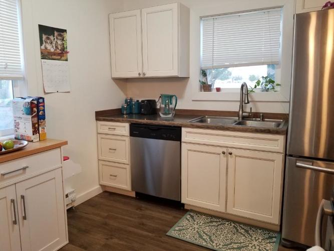 A kitchen with white cabinets and a stainless steel refrigerator.
