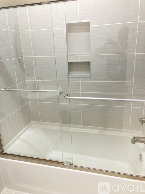 A bathroom with a glass shower door and a white tub.
