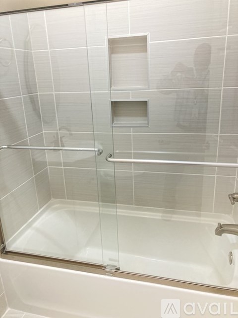 A bathroom with a glass shower door and a white tub.