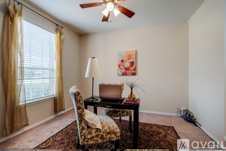 A room with a chair, a table, and a ceiling fan.