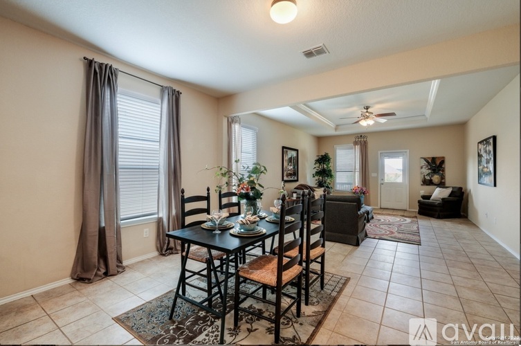 A dining room with a table set for six and a fan on the ceiling.
