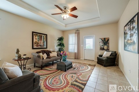 A living room with a ceiling fan and a rug on the floor.