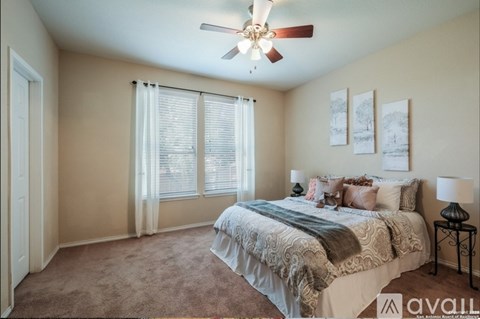 A bedroom with a bed, a ceiling fan, and a window with blinds.