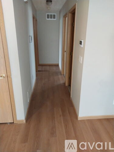 A long hallway with wood floors and white walls.