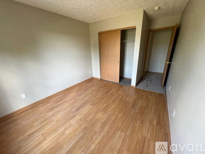 A room with wooden flooring and two doors.
