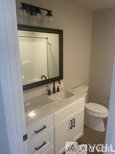 A bathroom with a white toilet and a sink with a mirror above it.