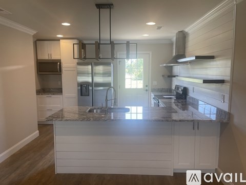 A modern kitchen with a granite countertop and white cabinets.