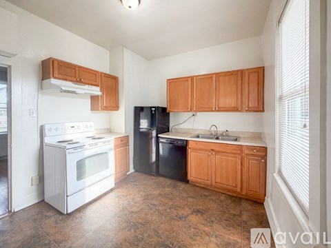 A kitchen with a white stove and black dishwasher.