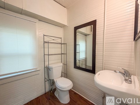 A white toilet sits in a bathroom next to a sink and a mirror.