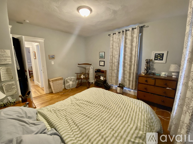 A bedroom with a bed in the foreground and a dresser with a mirror and lamp in the background.