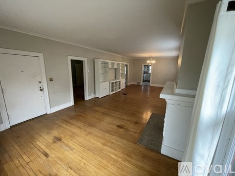 A spacious room with wooden flooring and white walls.