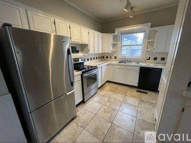 A kitchen with a stainless steel refrigerator and white cabinets.