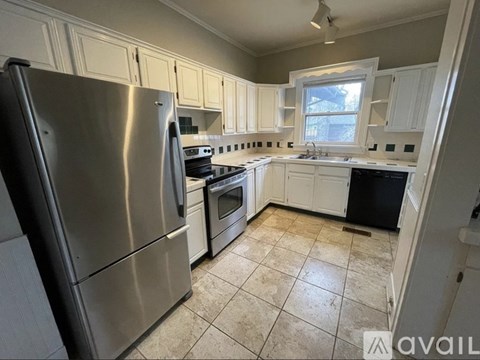 A kitchen with a stainless steel refrigerator and white cabinets.