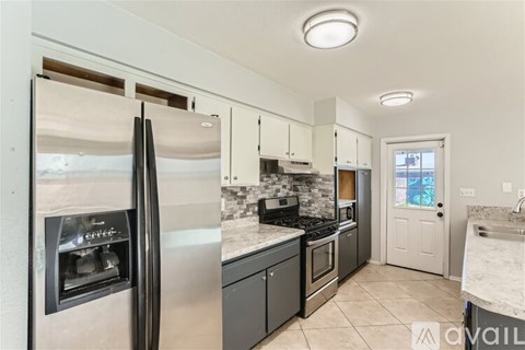 A kitchen with a refrigerator, oven, and sink.
