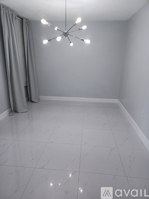 A room with a chandelier and a grey curtain.