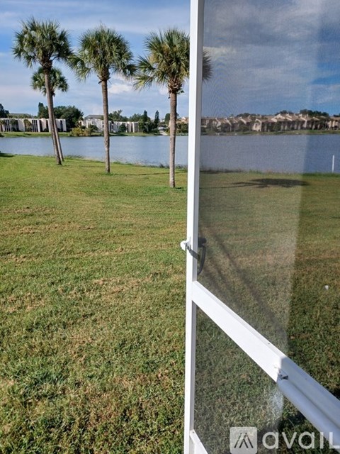 A white fence with a grassy field and trees in the background.
