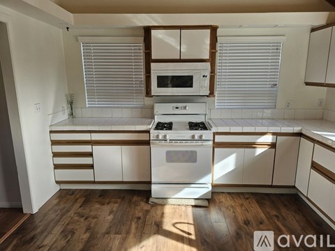 A white kitchen with a stove and a microwave.
