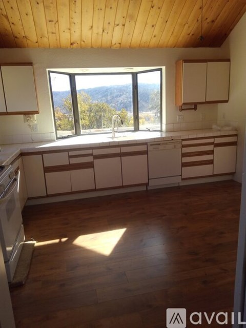 A kitchen with wooden floors and a window overlooking the mountains.