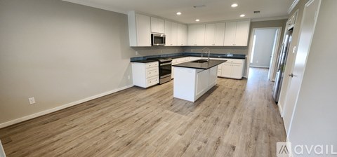A kitchen with white cabinets and a wooden floor.