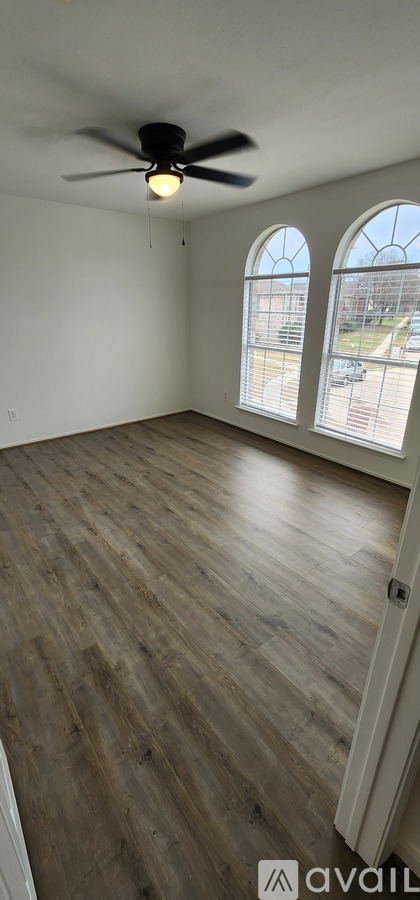 A room with a ceiling fan and wooden flooring.