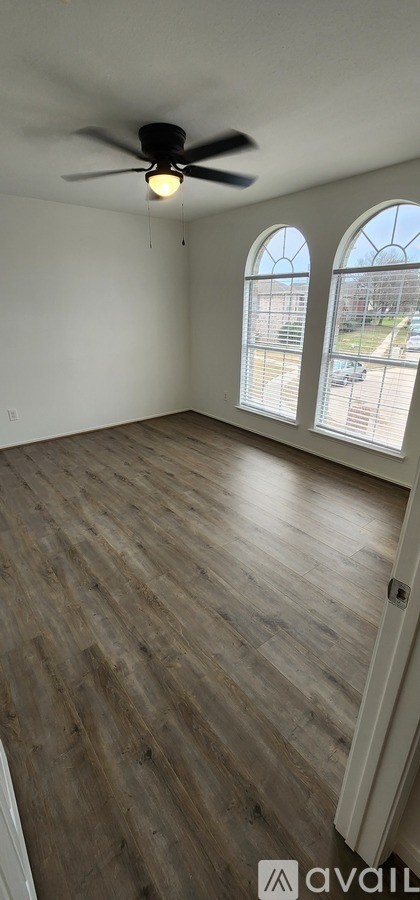 A room with a ceiling fan and wooden flooring.