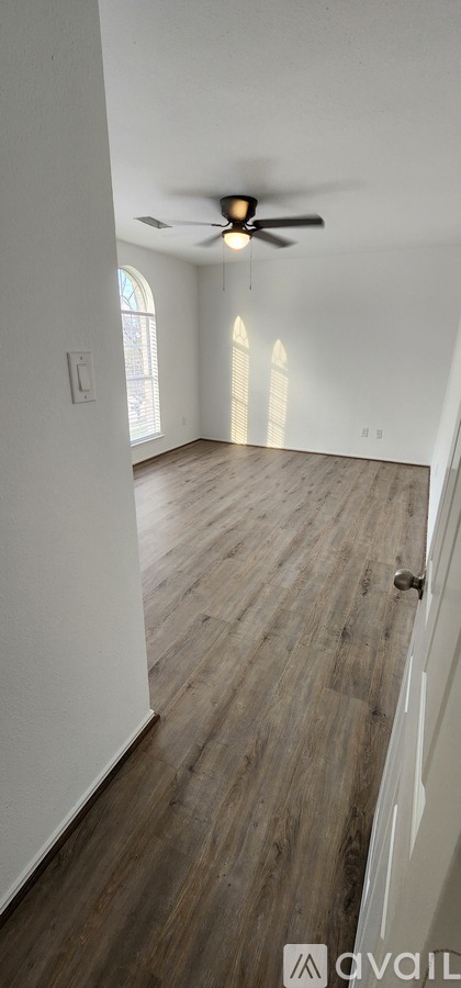 A room with a ceiling fan and wooden flooring.