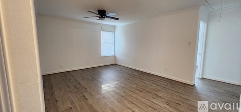 A spacious room with wooden flooring and a ceiling fan.