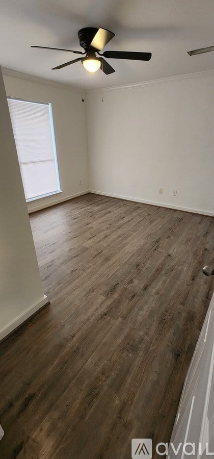 A room with a ceiling fan and wooden flooring.
