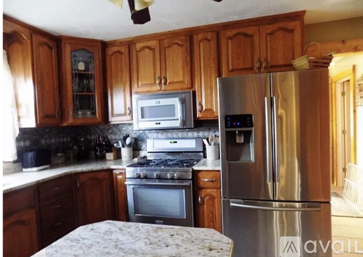A kitchen with wooden cabinets and a stainless steel refrigerator.