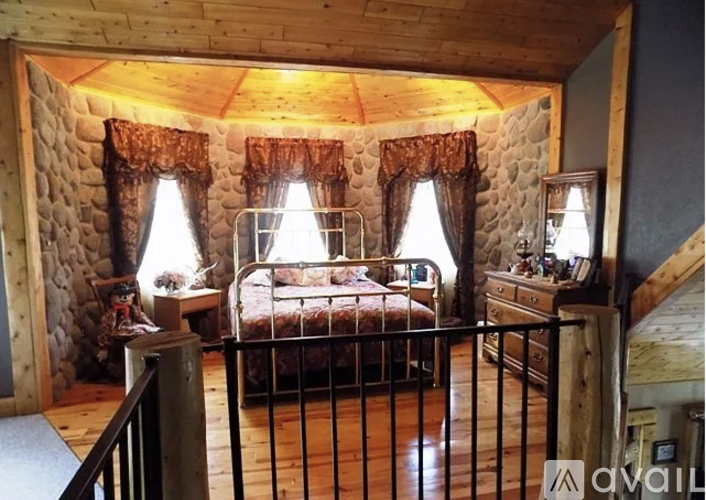 A bedroom with a bed, dresser, and window with curtains.