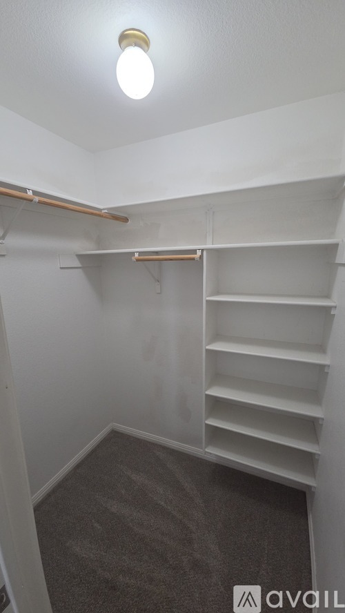 A small, empty room with a carpeted floor and a single light bulb on the ceiling.