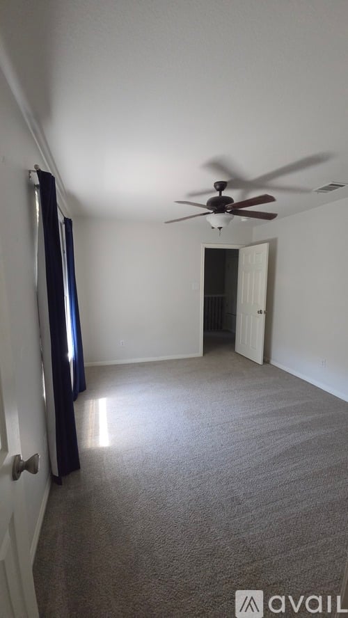 A room with a ceiling fan and carpeted floor.