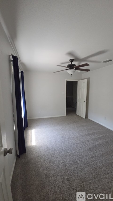 A room with a ceiling fan and carpeted floor.
