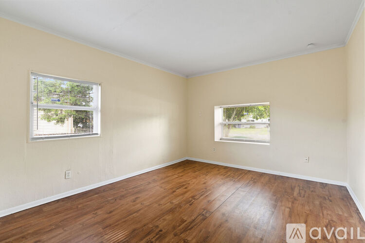 A room with wooden floors and two windows.