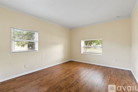 A room with wooden floors and two windows.