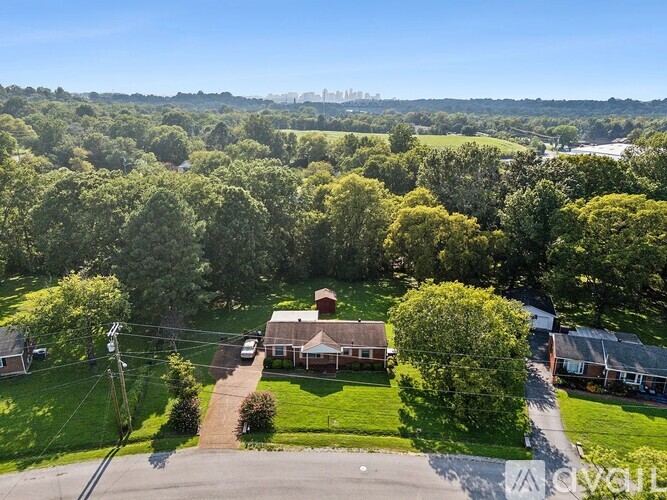 A house surrounded by green trees under a clear blue sky.