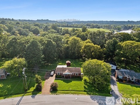 A house surrounded by green trees under a clear blue sky.