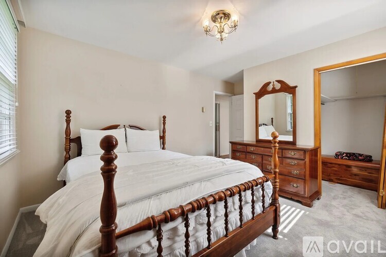 A bedroom with a large bed, a dresser, and a mirror.