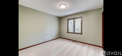A room with a window and a carpeted floor.