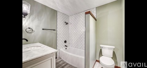 A white toilet is in a bathroom with a white tub and sink.
