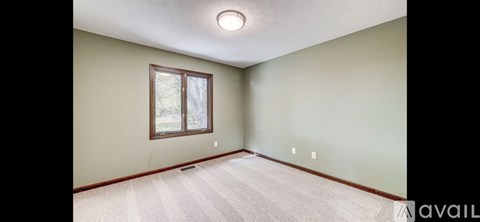 A room with a window and a carpeted floor.