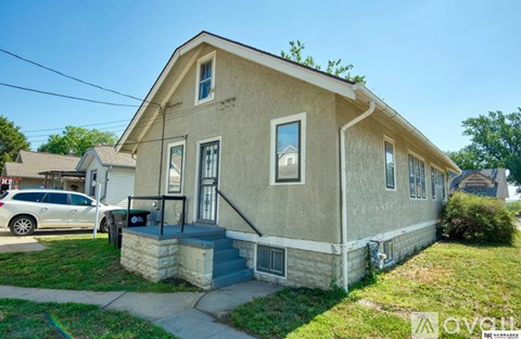 A beige house with a white car parked in front.