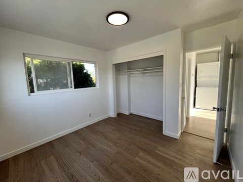 A room with wooden flooring and a window with a view of trees.
