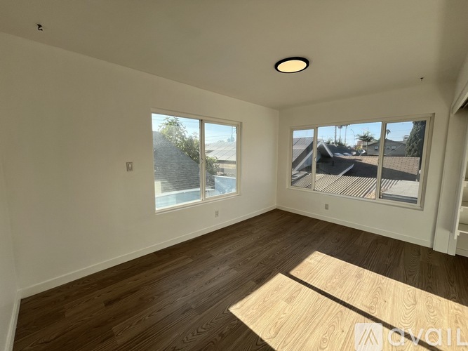 A room with wooden flooring and a large window overlooking a street.